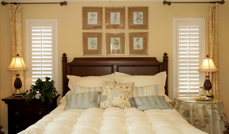 Bedroom with two tall plantation shutters on either side of bed in Raleigh 